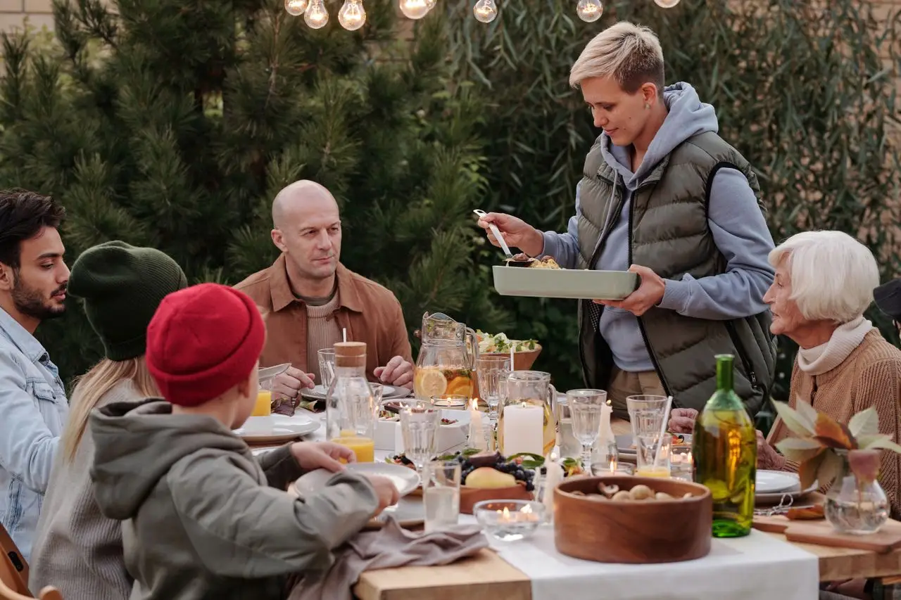 A cheerful multi-generational family enjoying dinner outdoors in a cozy garden