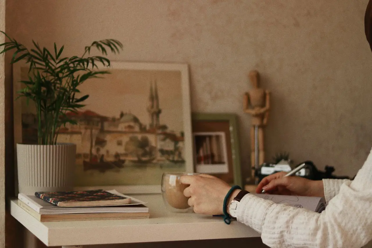 A peaceful indoor workspace with coffee, art, and a plant