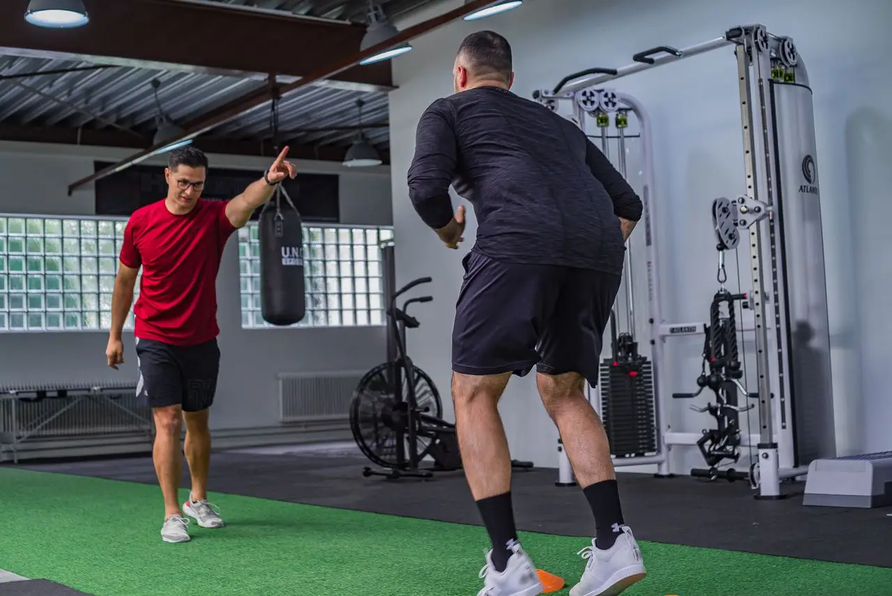 A personal trainer instructs an athlete during a focused gym workout session indoors
